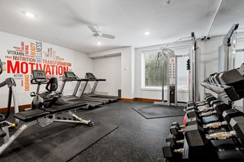 A gym with a row of treadmills and a wall with words related to fitness.